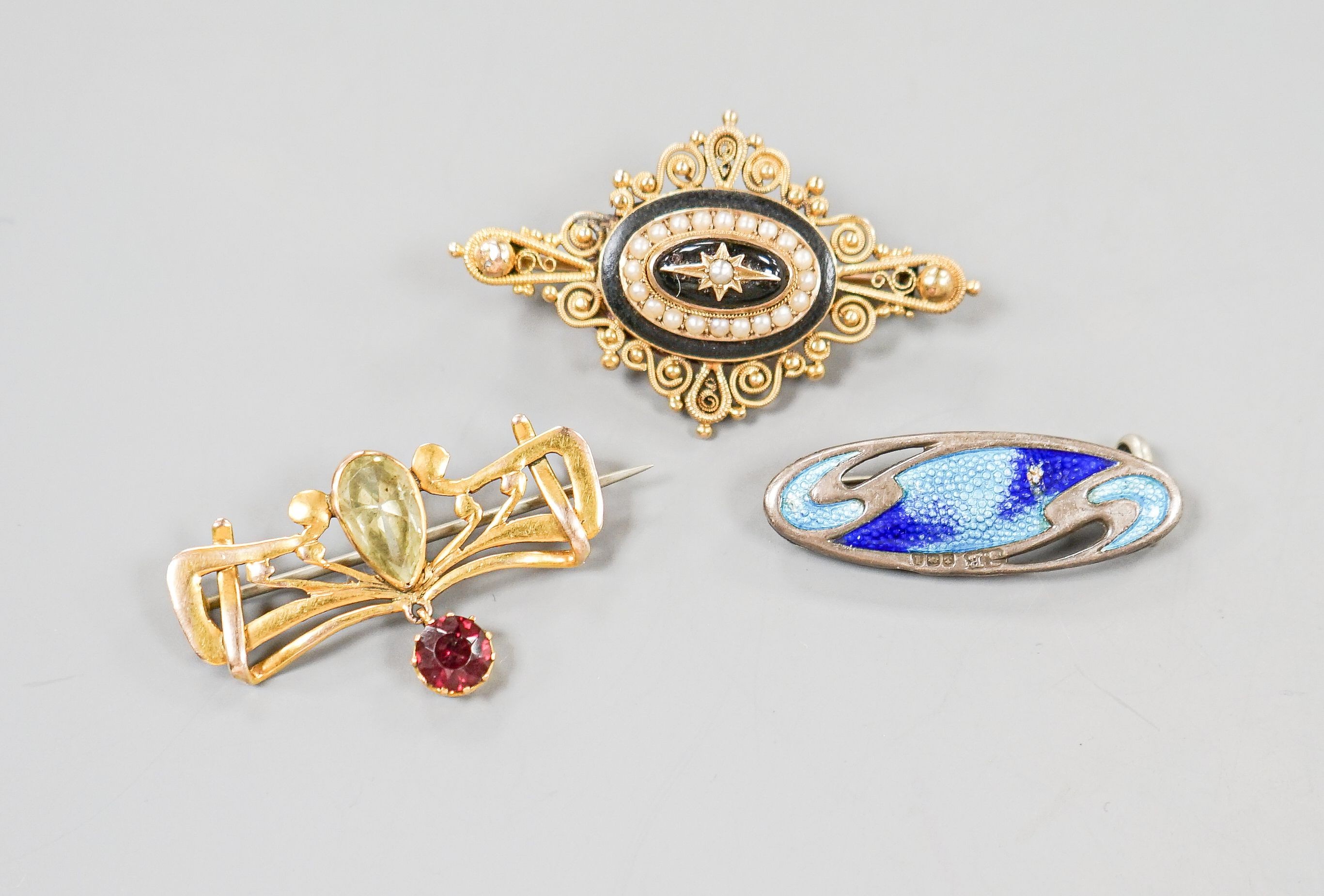 A Victorian yellow metal, black enamel and split pearl set quatrefoil brooch, 43mm, one other yellow metal and gem set drop brooch and a George V silver and enamel set brooch.